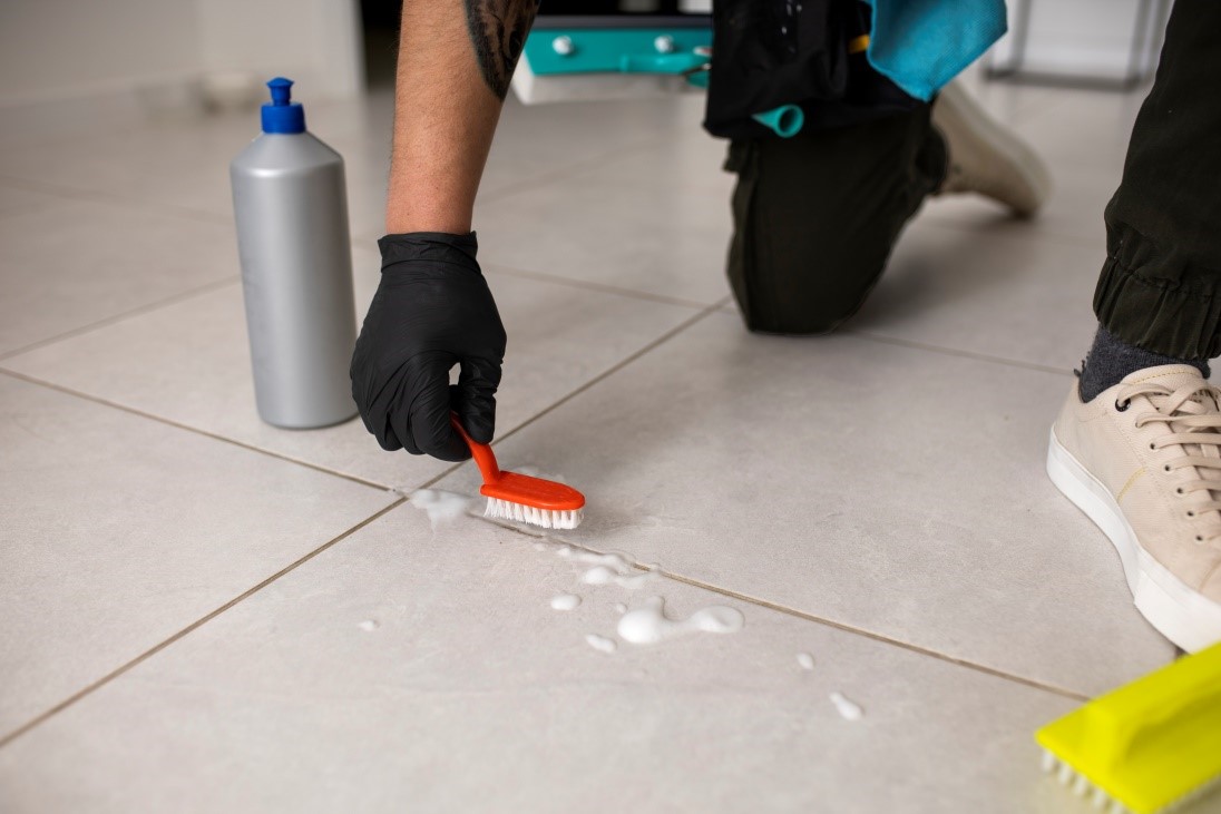 A person wearing a black glove and kneeling on the floor